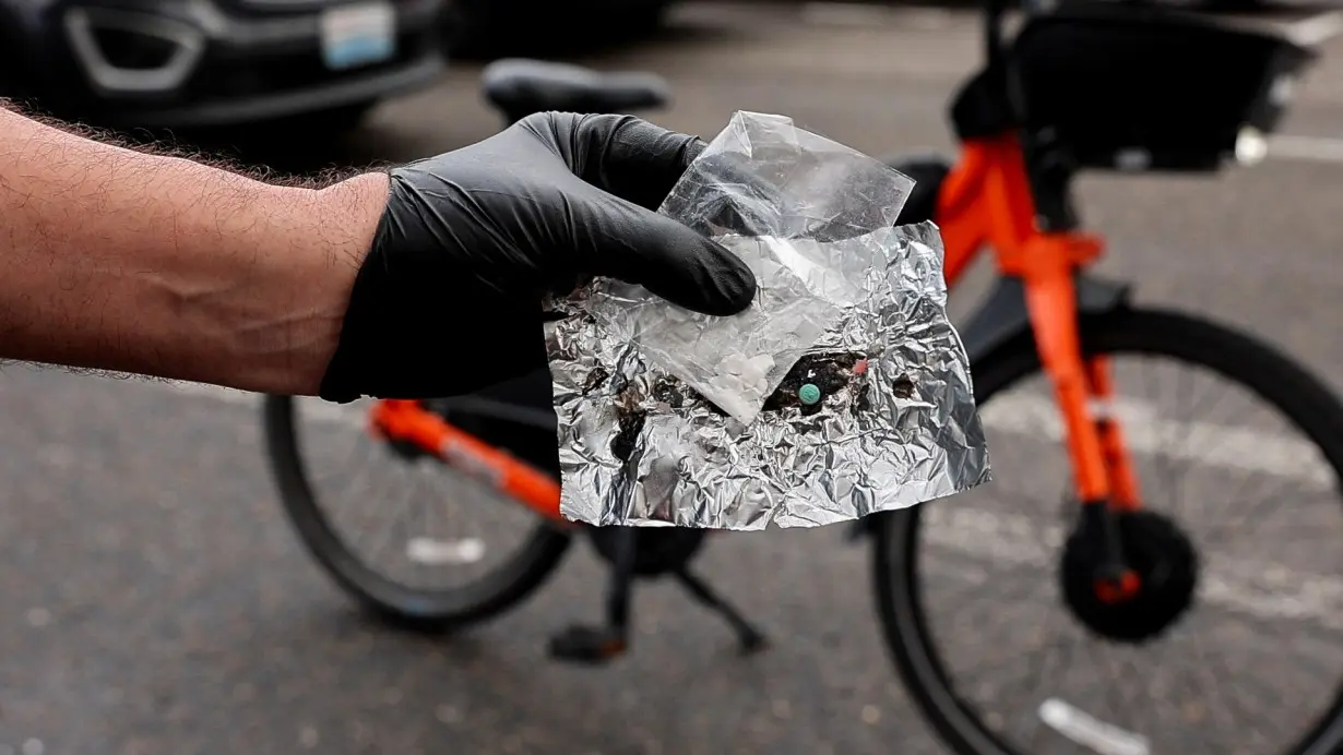 Portland police officer David Baer holds up a blue oxycodone pill and a small bag of fentanyl