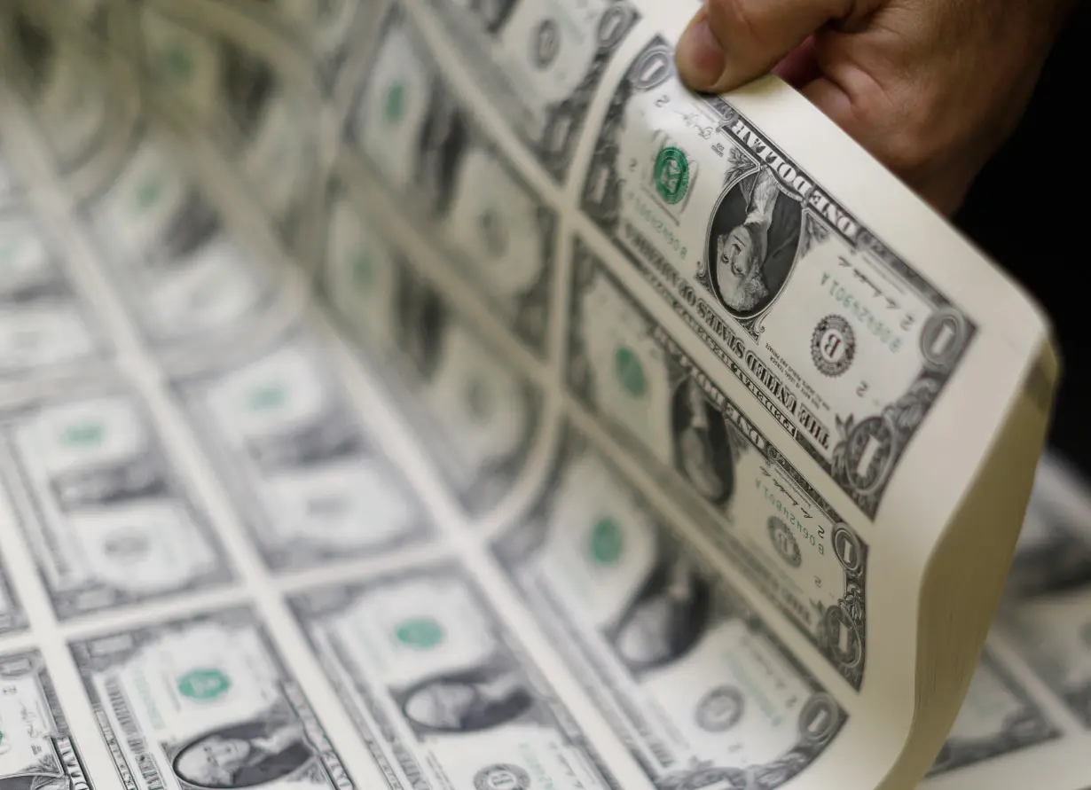 United States one dollar bills are curled and inspected during production at the Bureau of Engraving and Printing in Washington