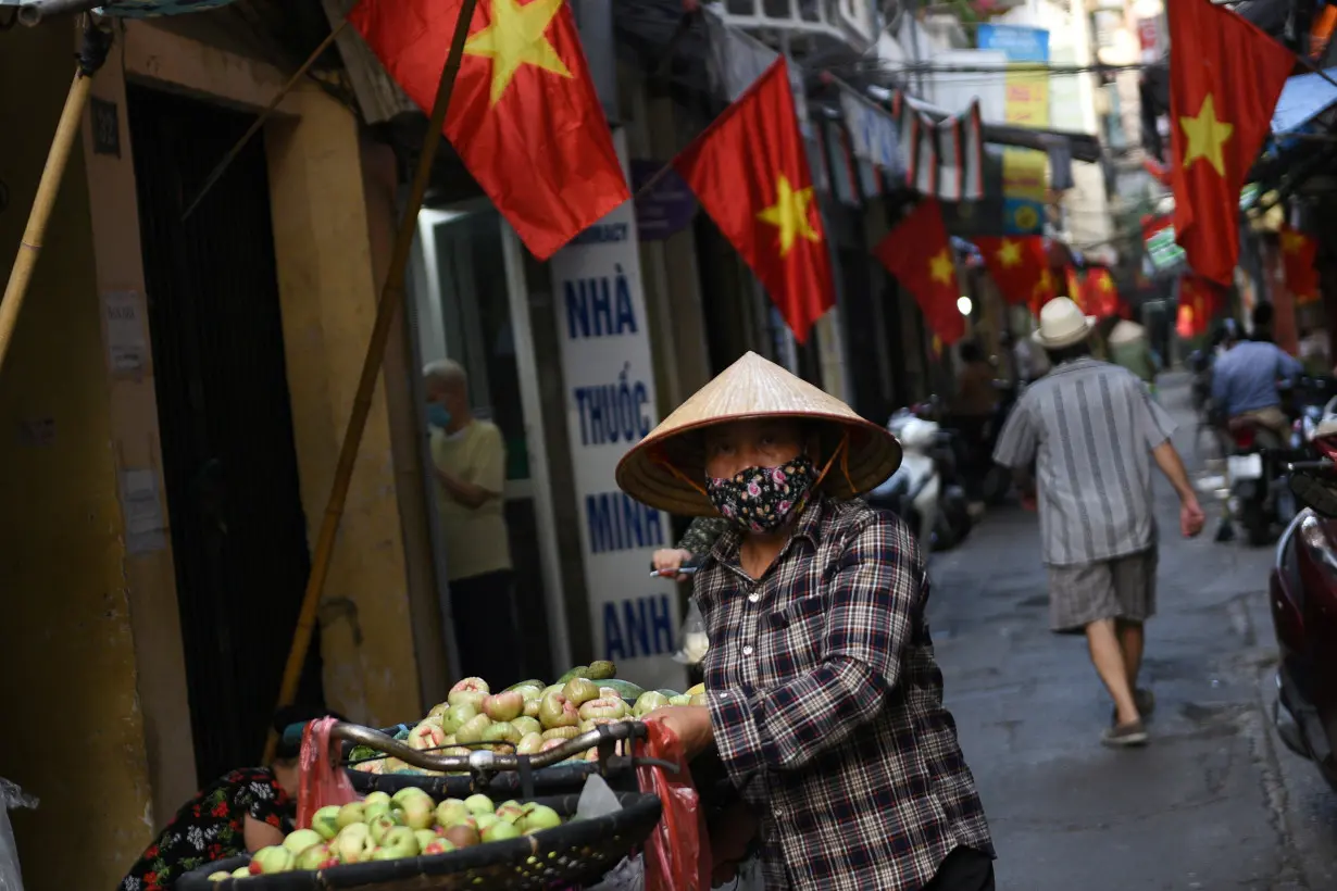 A vendor walks in an alley decorated with national flags ahead of the upcoming elections in Hanoi