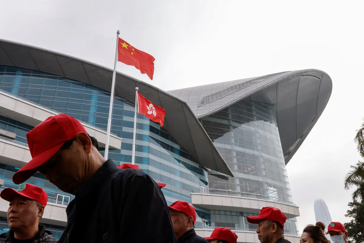 FILE PHOTO: Chinese tourists walk in front of the Chinese and Hong Kong flags, outside the Convention and Exhibition Centre, in Hong Kong