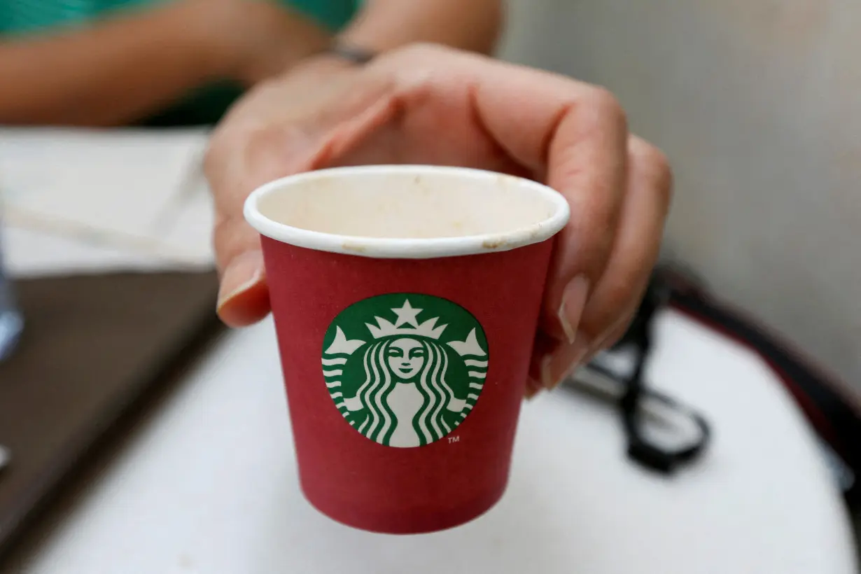 FILE PHOTO: A woman displays a red Starbucks cup at a Starbucks cafe in Beirut