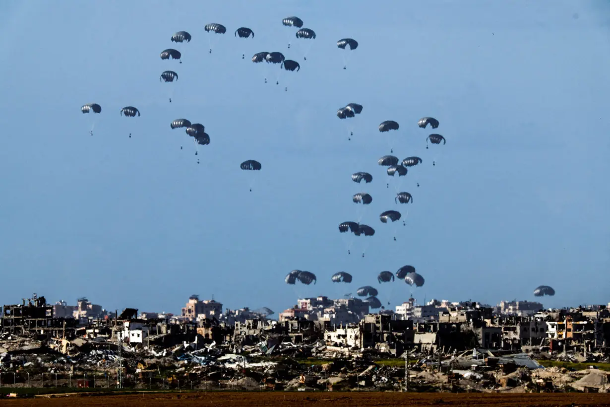 Packages dropped from a military aircraft fall towards northern Gaza, as seen from Israel