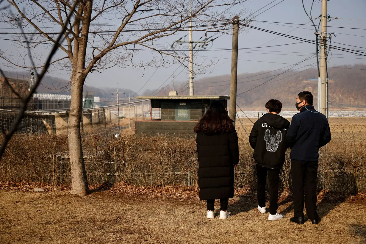 FILE PHOTO: A North Korean defector and his children stand in front of a barbed wire fence near the demilitarised zone separating the two Koreas, in Paju