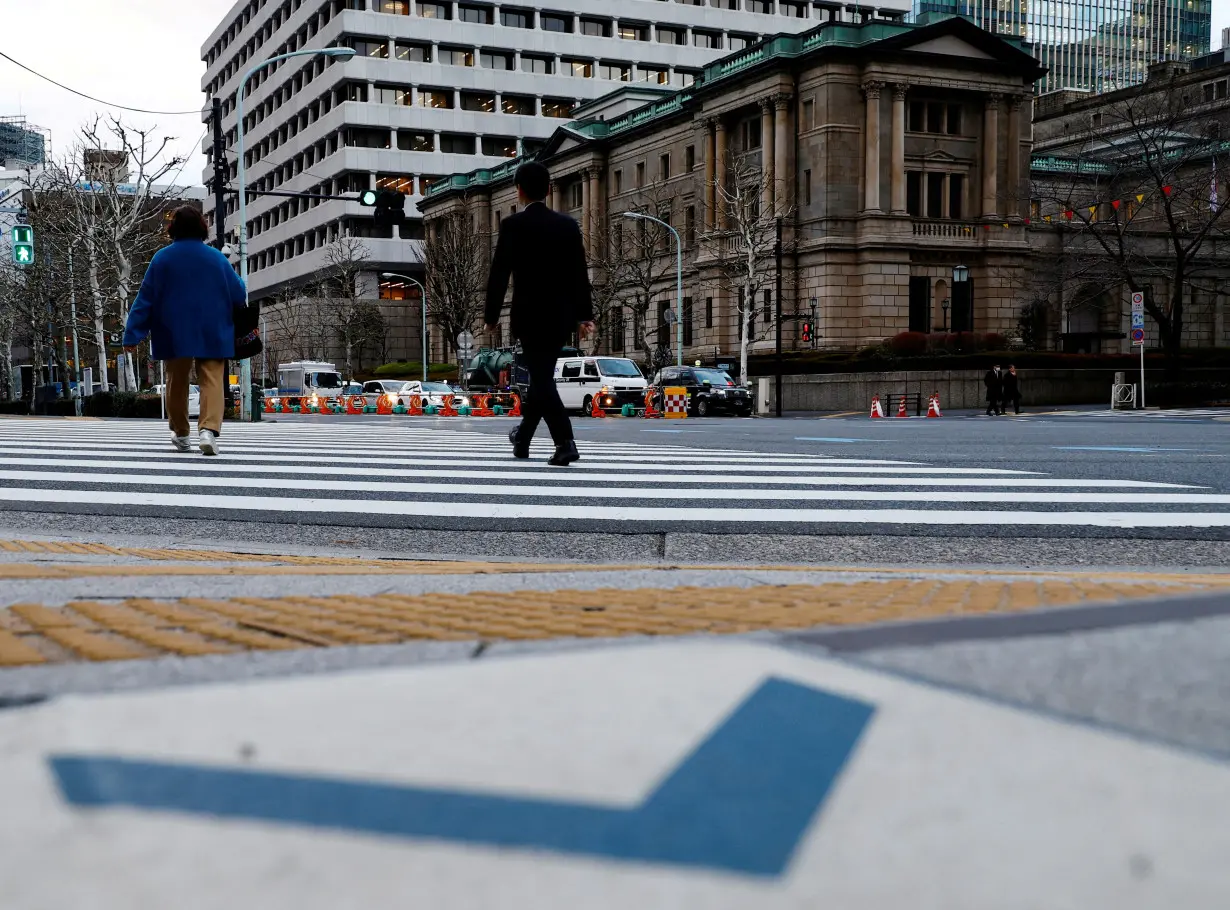 FILE PHOTO: People walk in front of the Bank of Japan building in Tokyo