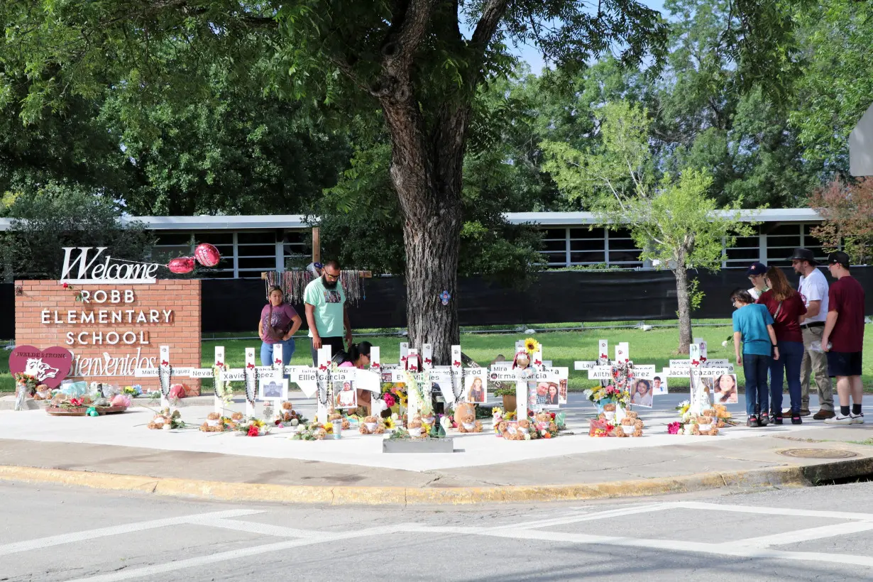 FILE PHOTO: People visit a memorial for the 21 victims of a mass shooting at Robb Elementary School in Uvalde