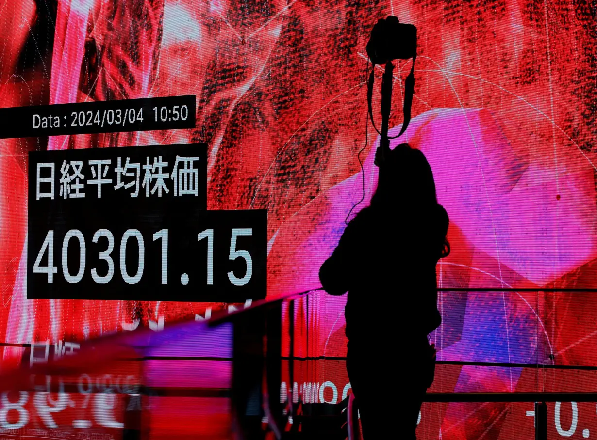 FILE PHOTO: A photographer takes a photo of an electronic screen displaying Japan's Nikkei share average in Tokyo