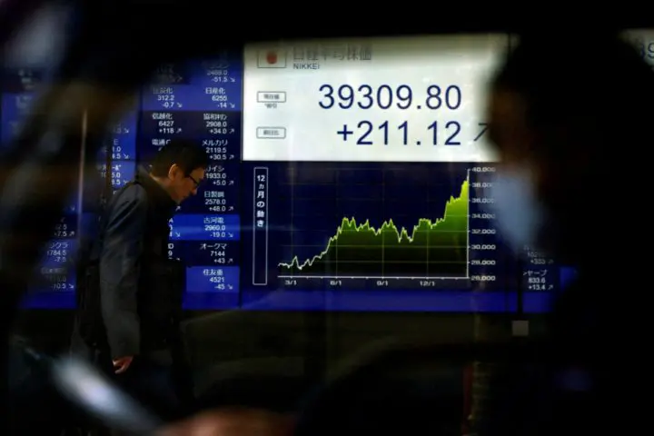 FILE PHOTO: An electronic screen displaying Japan's Nikkei share average and stock prices is seen through a car in Tokyo
