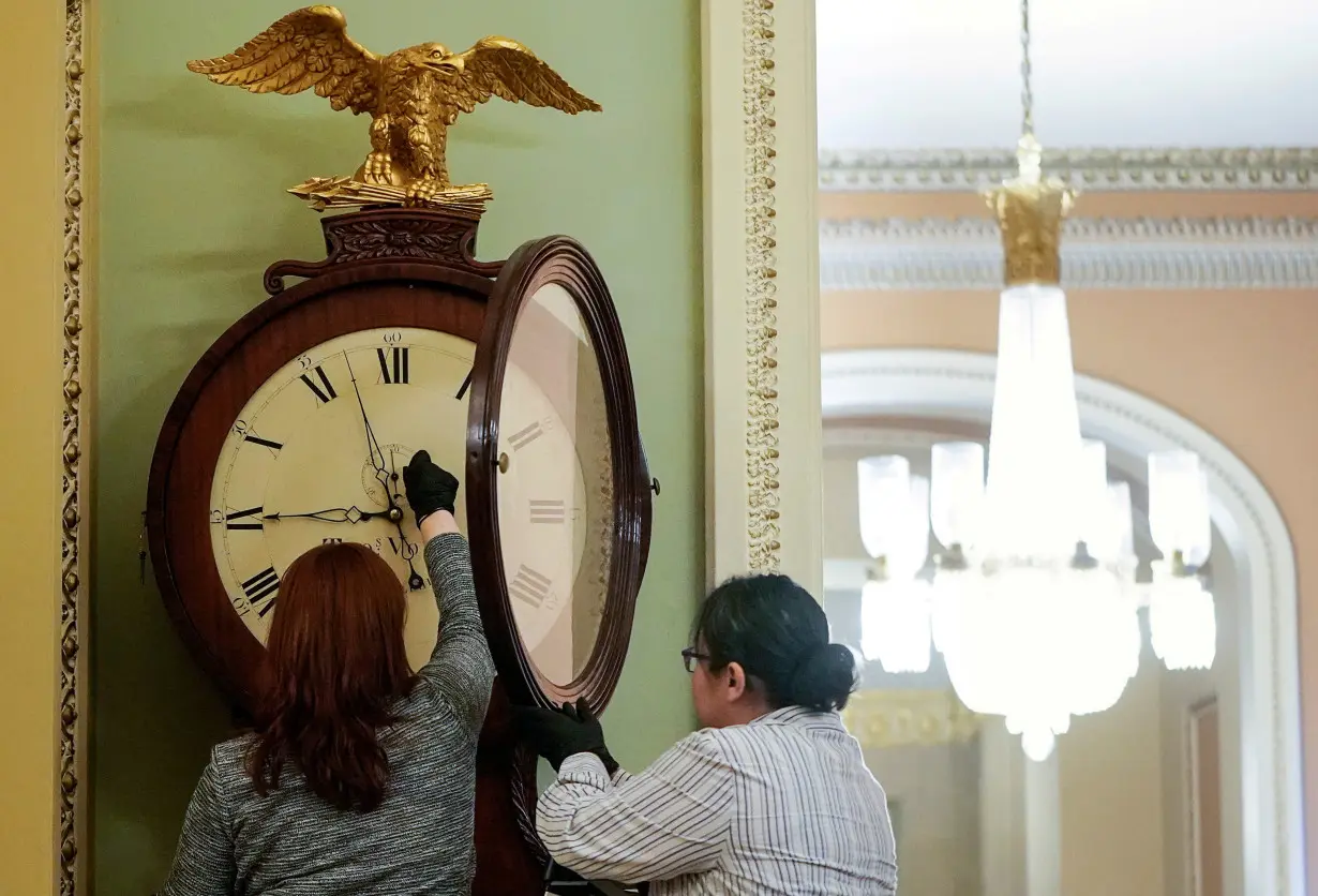 FILE PHOTO: Architect of the Capitol workers wind Ohio Clock on first day of Trump impeachment trial in Washington