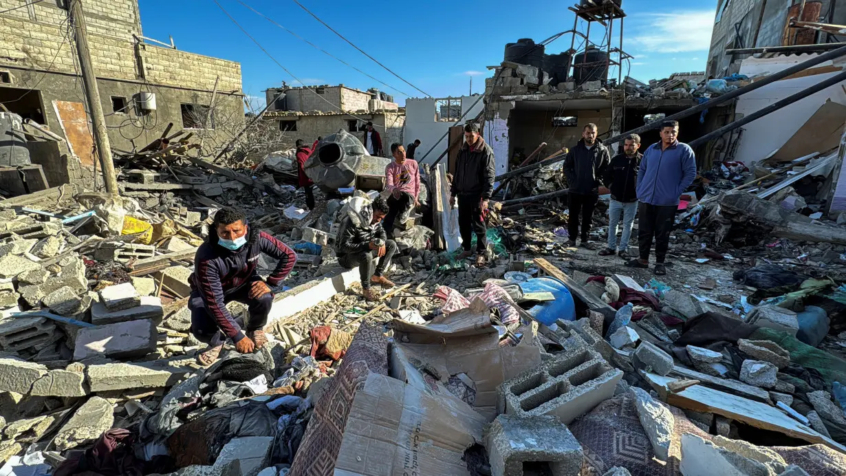 Palestinians inspect the site of an Israeli strike on a house, in Rafah