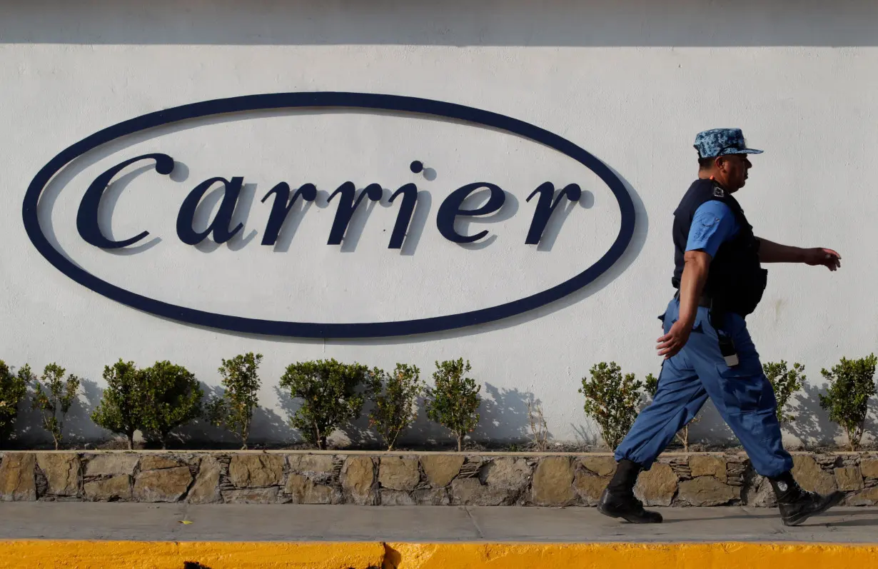 FILE PHOTO: Private security guard walks past a logo of Carrier Corp outside the air conditioner plant, a unit of United Technologies Corp, in Santa Catarina