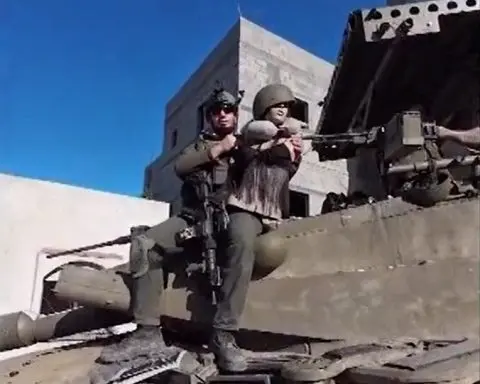 An Israeli soldier sits on top of a tank holding a female mannequin in a screengrab of a video