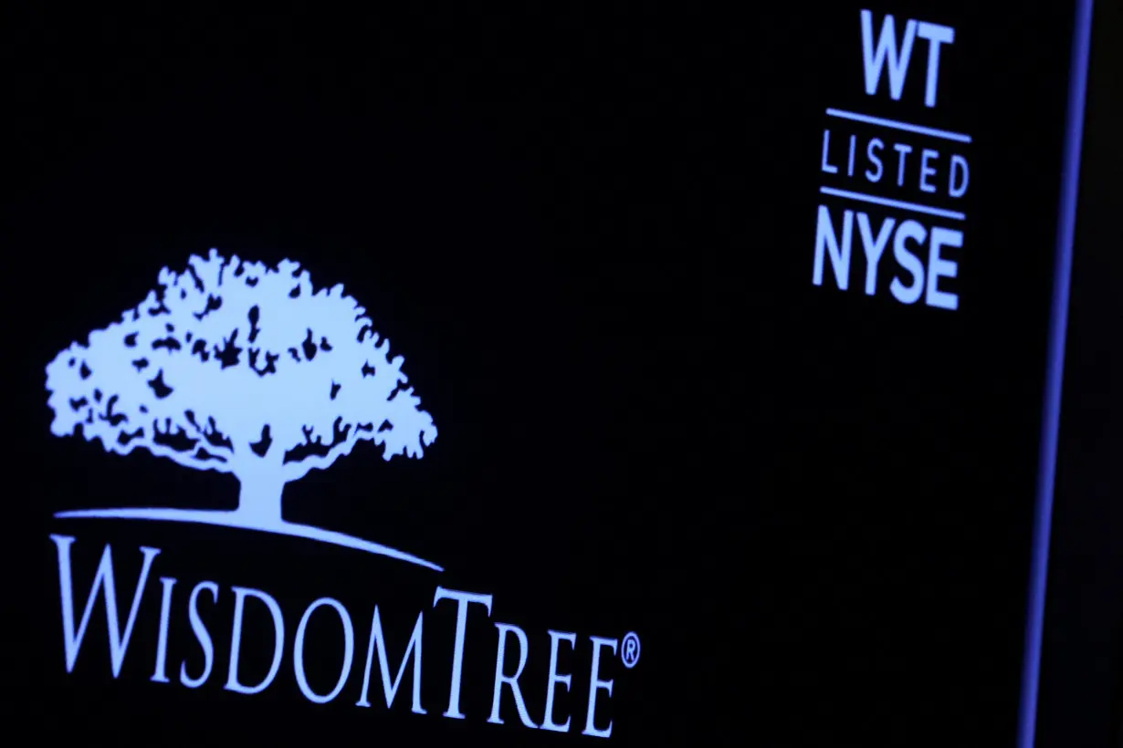 A screen displays the logo and trading information for WisdomTree following its debut on the floor of the NYSE in New York