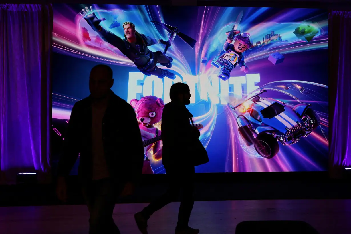 FILE PHOTO: People in silhouette walk by a Fortnite gaming digital monitor during an event in New York City