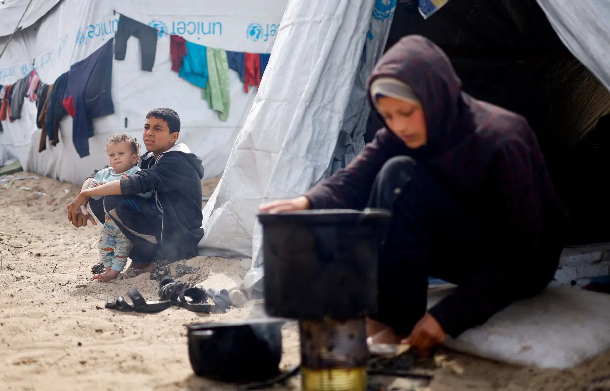 FILE PHOTO: Displaced Palestinians, who fled their houses due to Israeli strikes, shelter at a tent camp, in Rafah