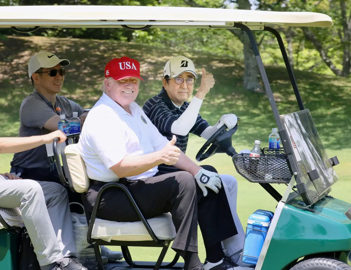 FILE PHOTO: U.S. President Donald Trump sits on a cart as Japanese Prime Minister Shinzo Abe drives the cart as they play golf at Mobara Country Club in Mobara