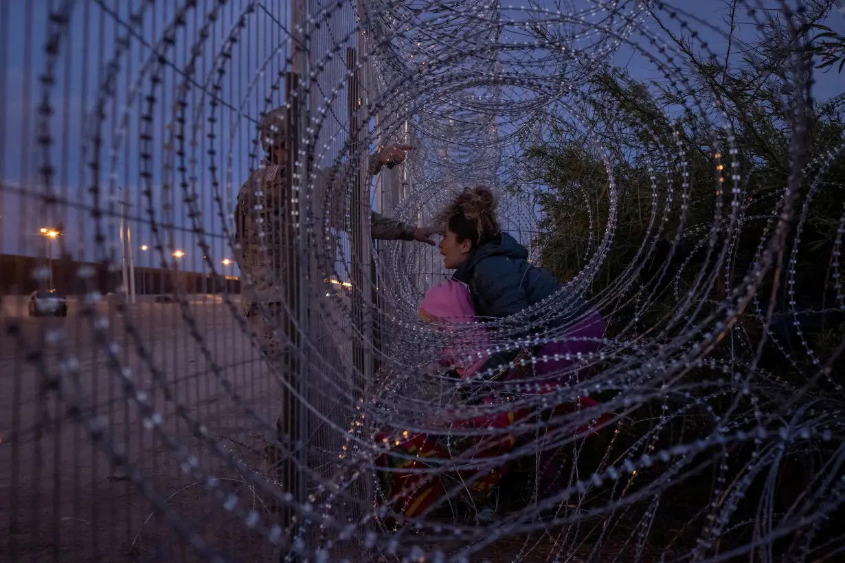 Migrant woman shouts as soldier halts her from breaching razor wire fence in El Paso