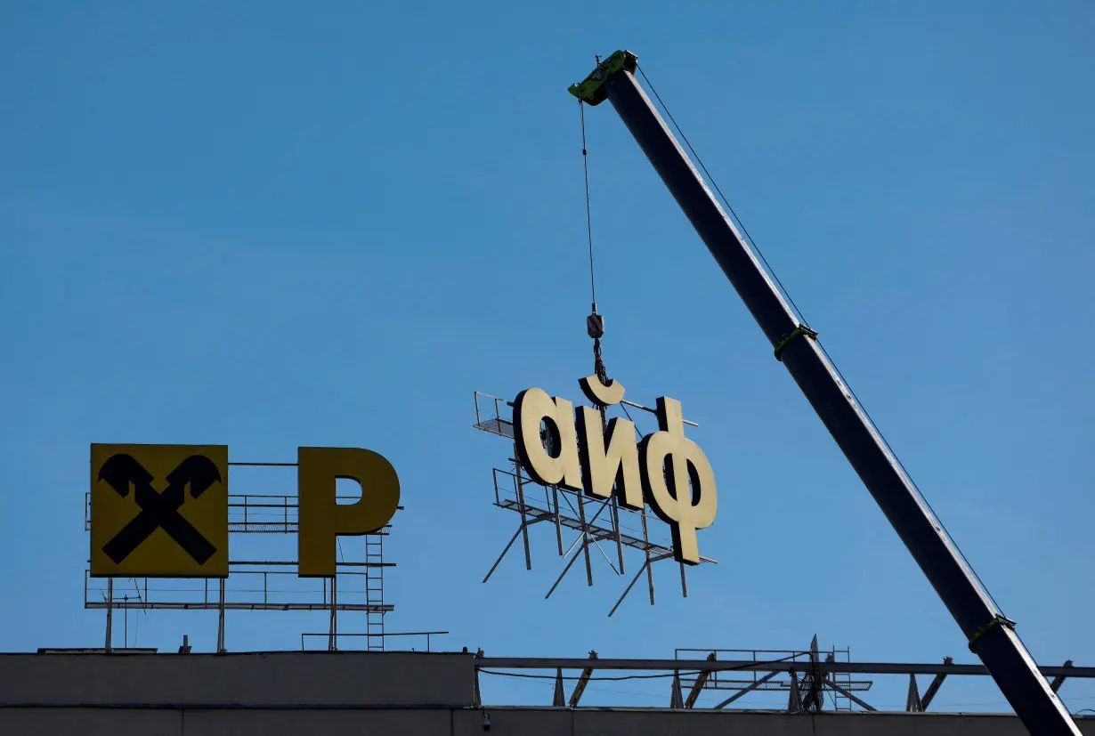 FILE PHOTO: Workers remove a signboard advertising Raiffeisen Bank in Moscow