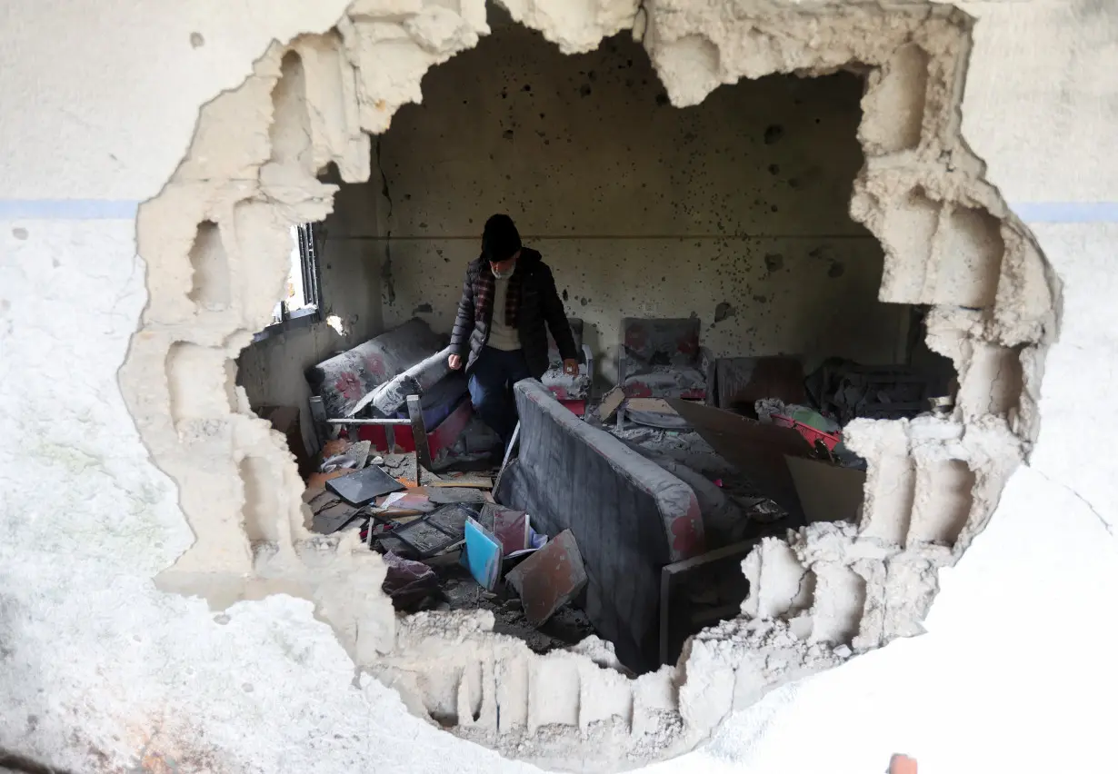 Hussein Jaber walks inside his damaged house in Mhaibib