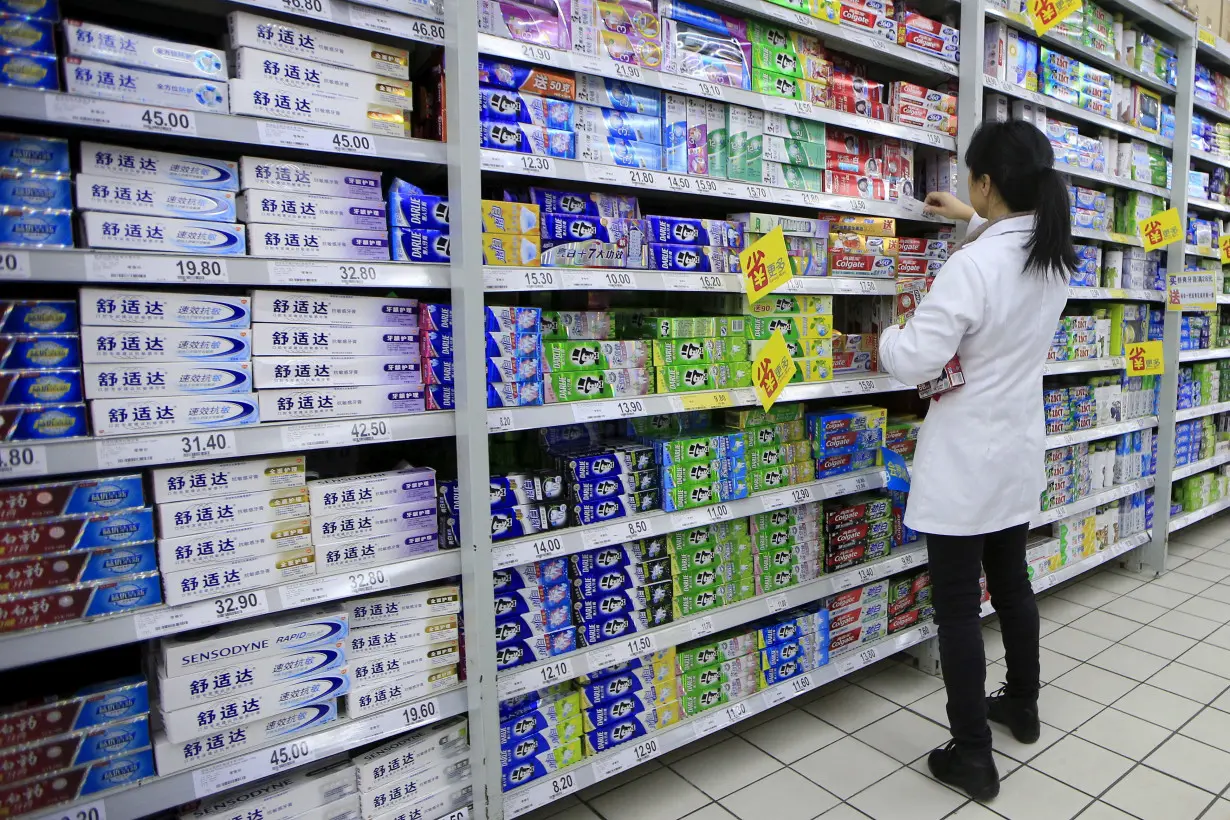 FILE PHOTO: A salesperson arranges toothpaste products on a shelf at a supermarket in Shanghai