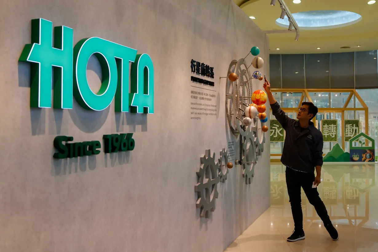 Morris Wu, Director of Sales and Marketing of Hota Industrial demonstrates a model of gears featuring planets of the Solar system by the company logo, in Taichung