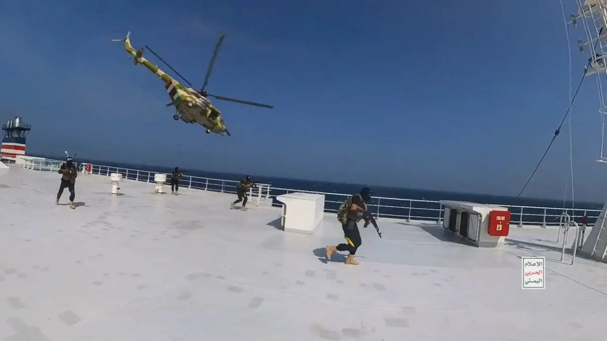 Houthi military helicopter hovers over the Galaxy Leader cargo ship as Houthi fighters walk on the ship's deck in the Red Sea