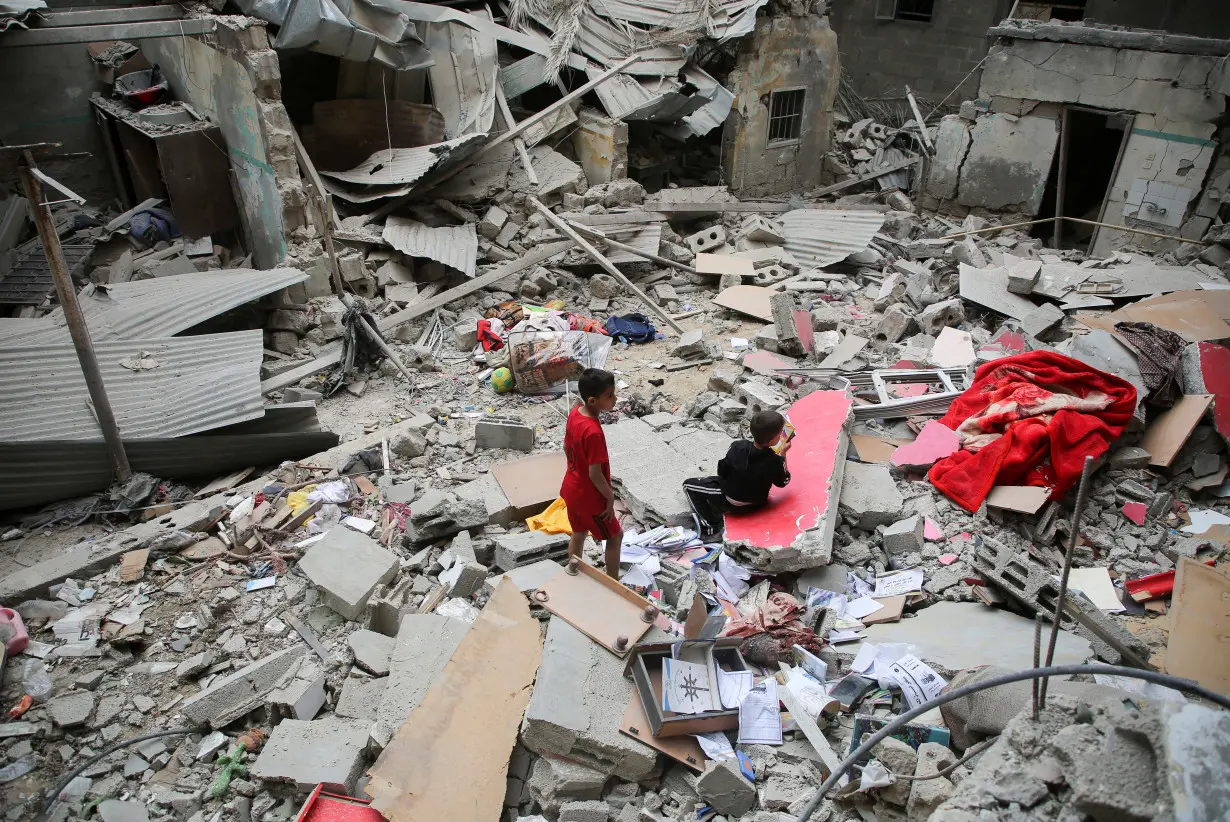 Palestinian children inspect the site of an Israeli strike on a house, in Rafah