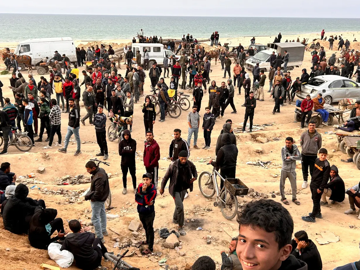 Palestinians gather as they wait for trucks carrying bags of flour to arrive, near an Israeli checkpoint, amid the ongoing conflict between Israel and Hamas, in Gaza City