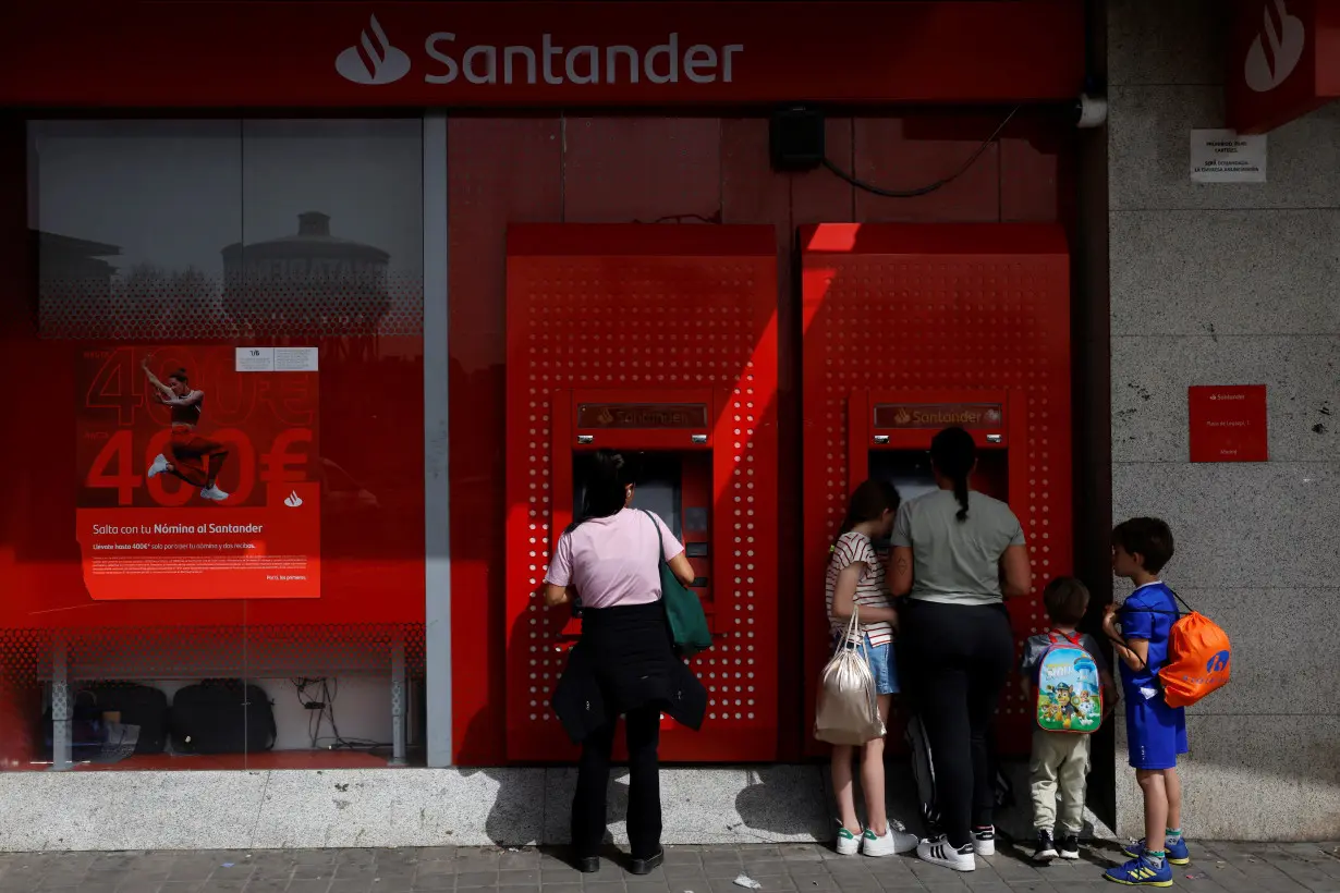 People use an ATM machine at a Santander bank branch in Madrid