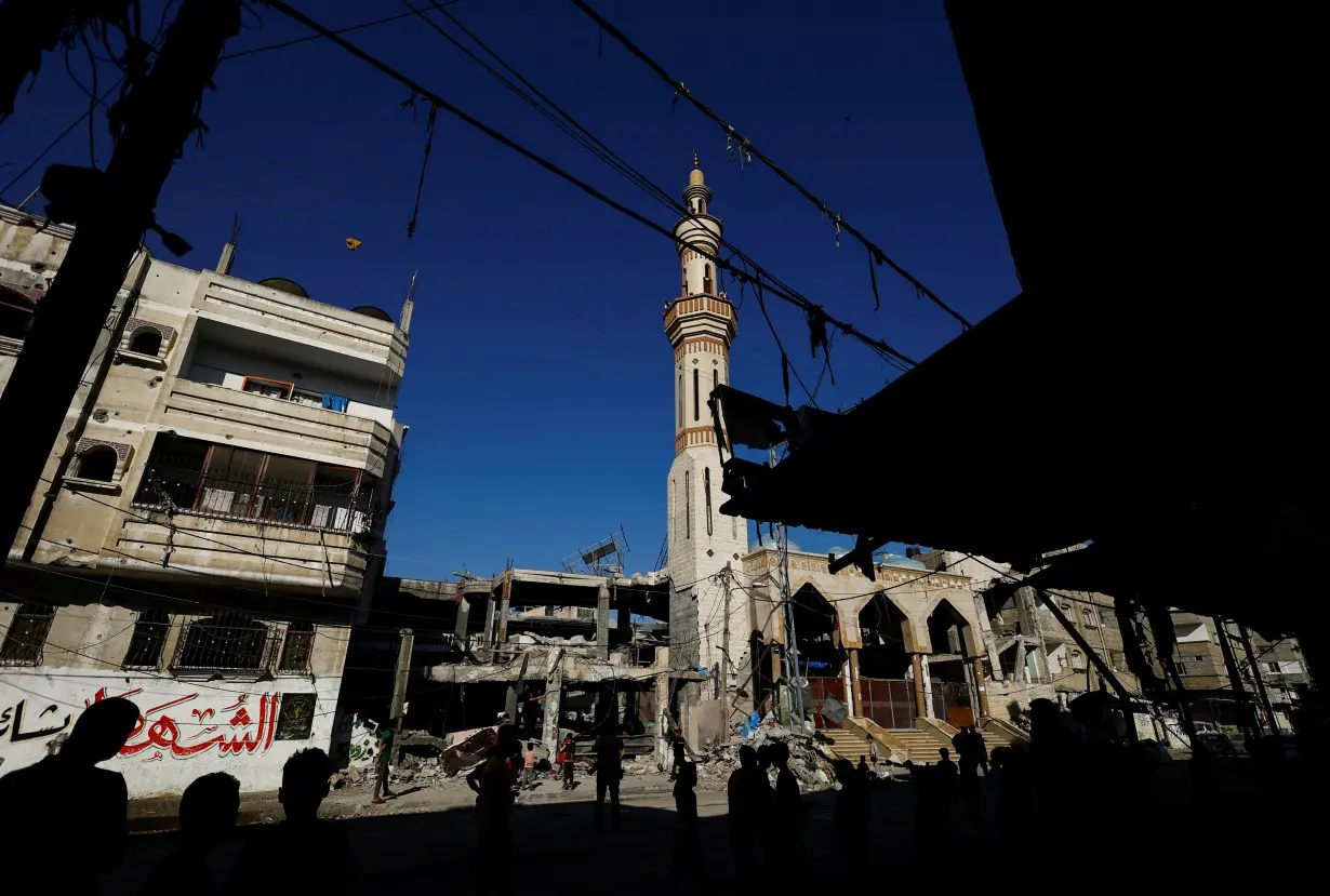 Palestinians stand near the site of an Israeli strike on a house, in Rafah