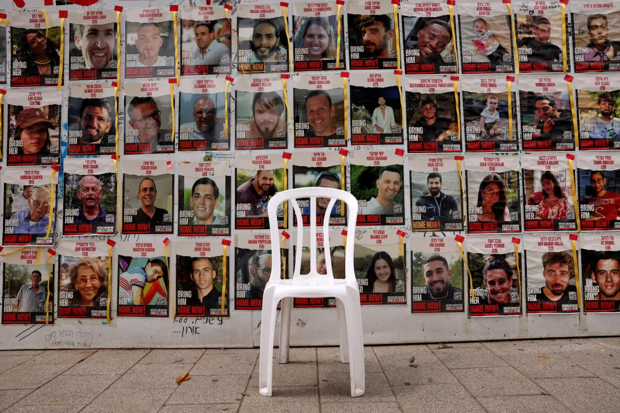 Chair is left in front of posters with pictures of hostages who were kidnapped during the deadly October 7 attack on Israel by Hamas, in Tel Aviv