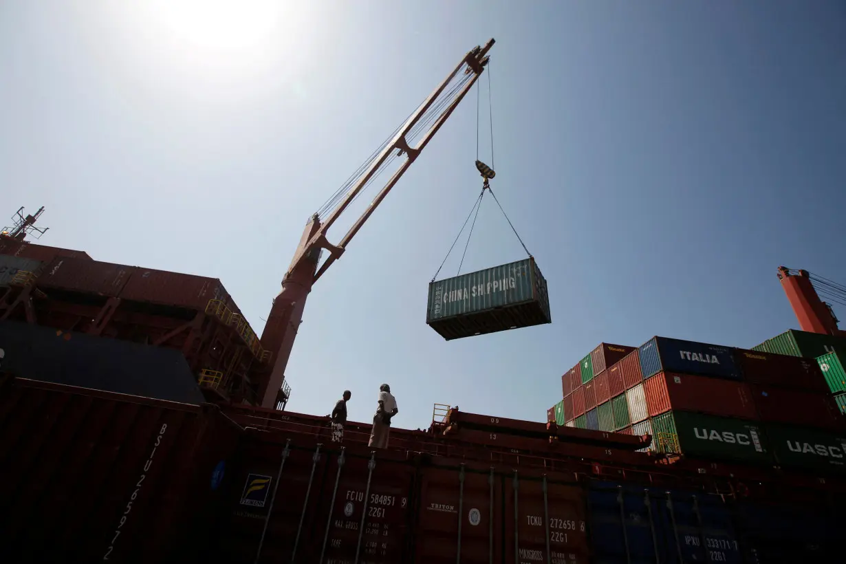 FILE PHOTO: Workers look on as a ship uses its crane to unload containers at a container terminal at the Red Sea port of Hodeidah