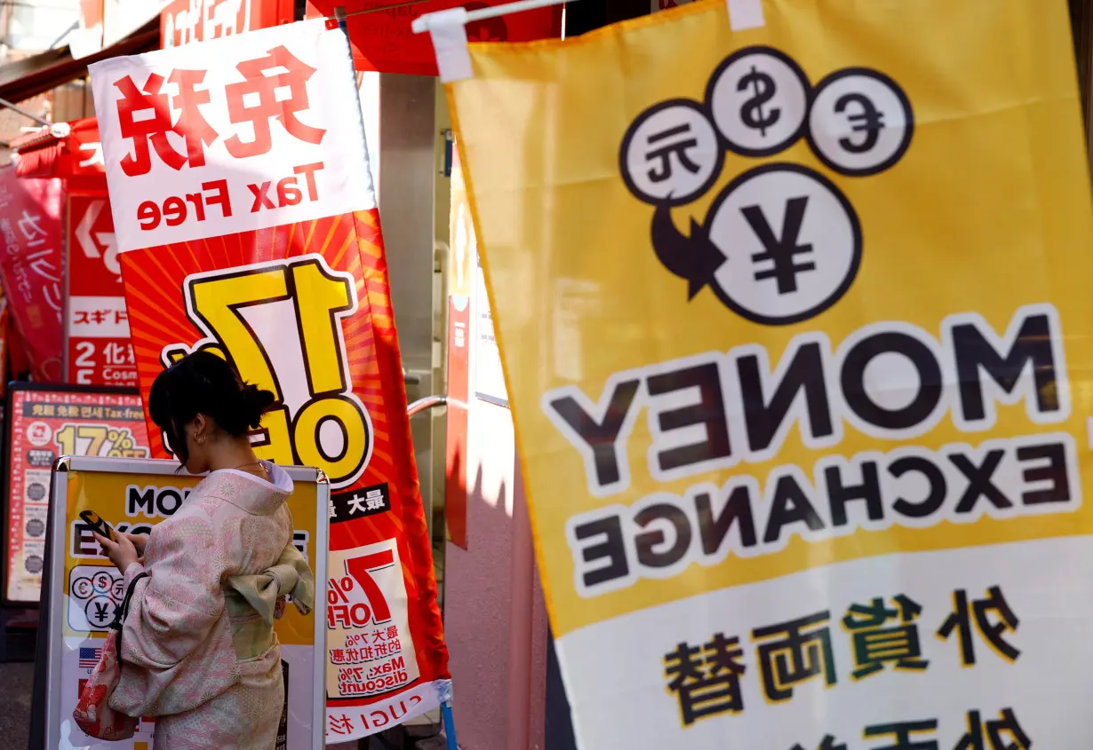 A foreign tourist wearing Kimono stands next to a sign of a currency exchange at Asakusa district in Tokyo