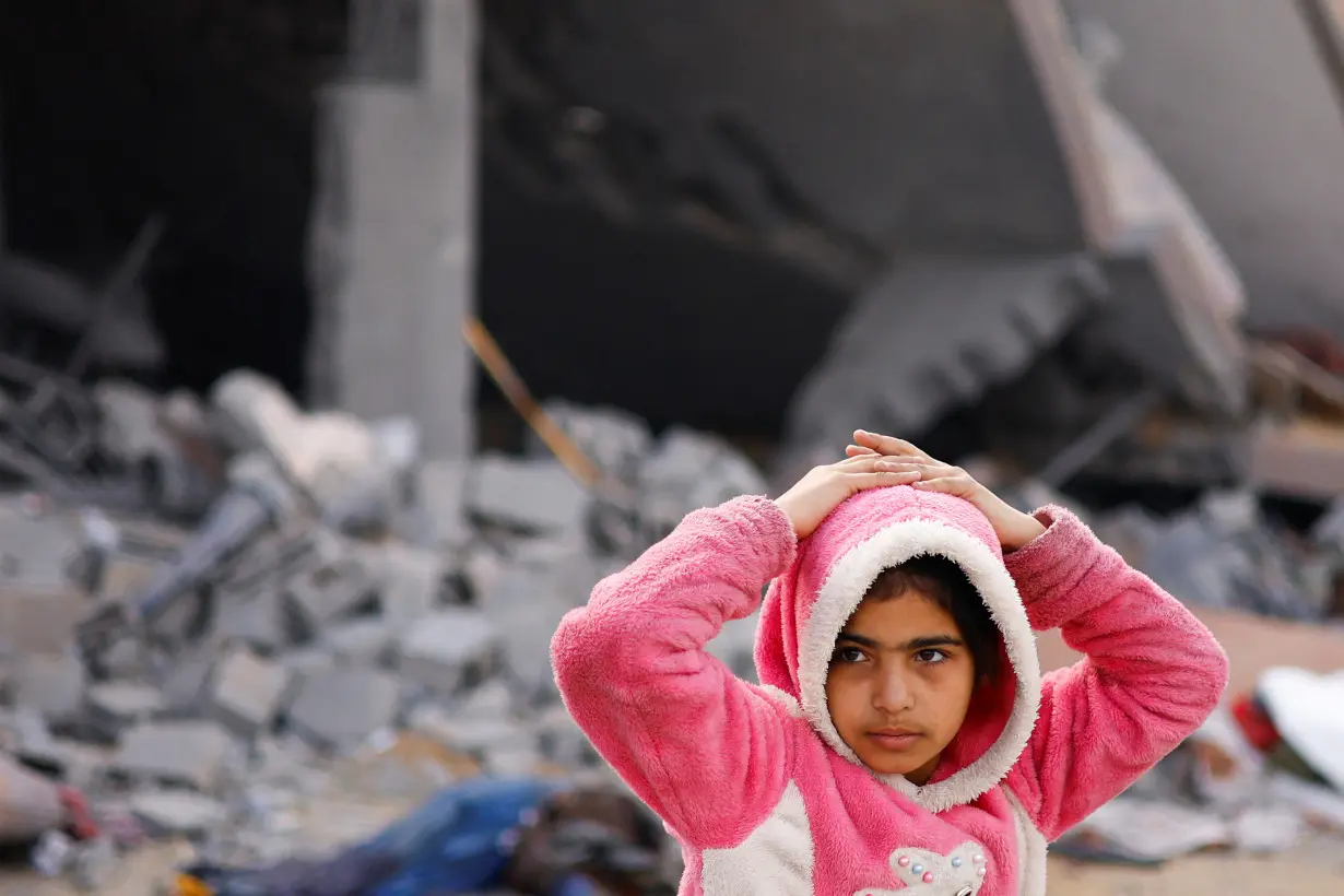 A Palestinian child gestures near a house hit by an Israeli strike, in Rafah in the southern Gaza Strip