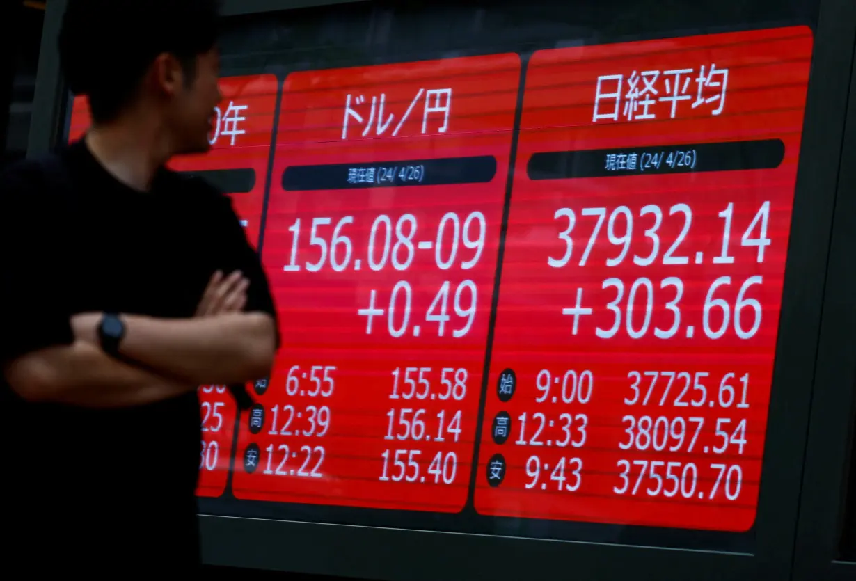 A passerby looks at an electric screen displaying current Nikkei share average and Japanese Yen exchange rate against the U.S. dollar in Tokyo