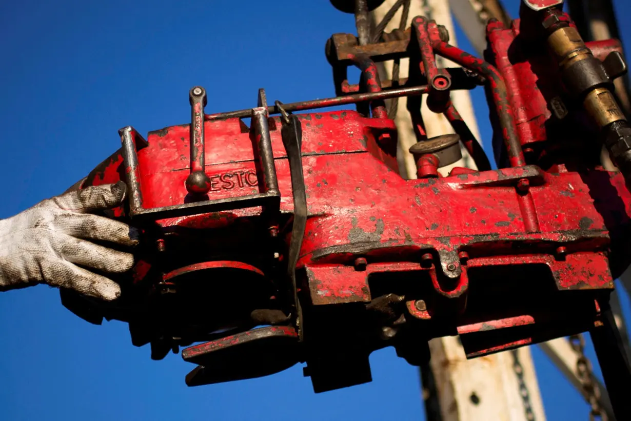 FILE PHOTO: A man works on the rig of an oil drilling pump site in McKenzie County outside of Williston