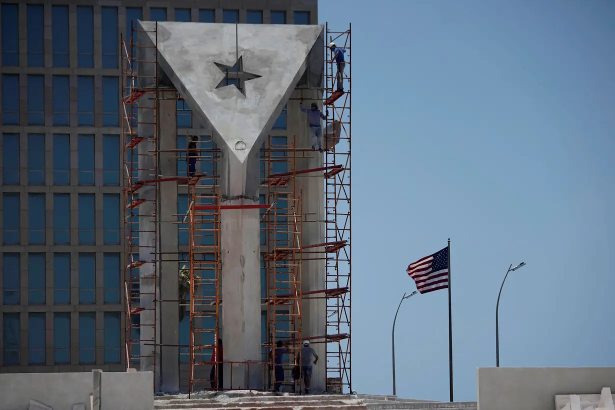 Men work in a monument in front of the U.S. Embassy in Havana