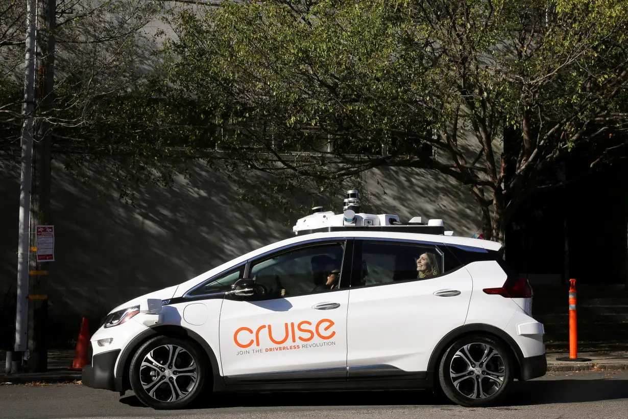 FILE PHOTO: A woman smiles in the back seat of a self-driving Chevy Bolt EV car during a media event by Cruise, GM’s autonomous car unit, in San Francisco