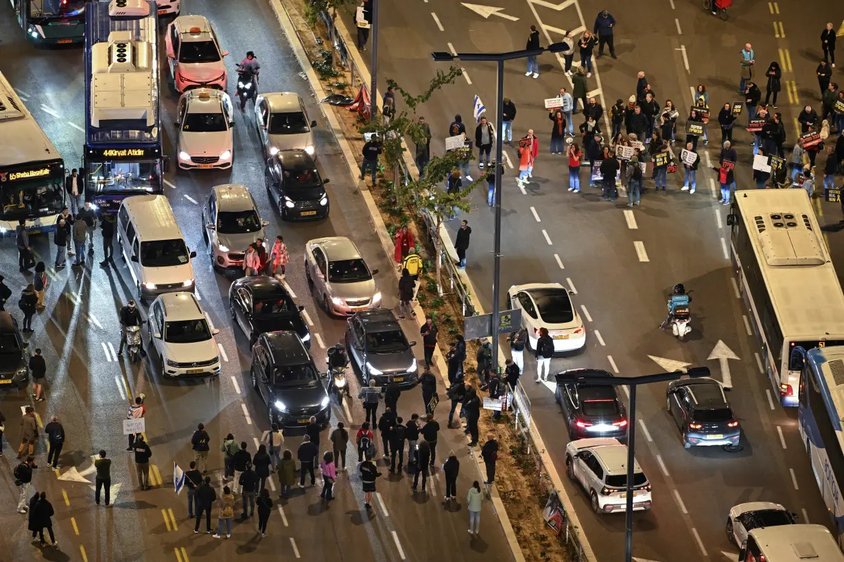 Demonstrators hold signs as they block traffic during rally in Tel Aviv