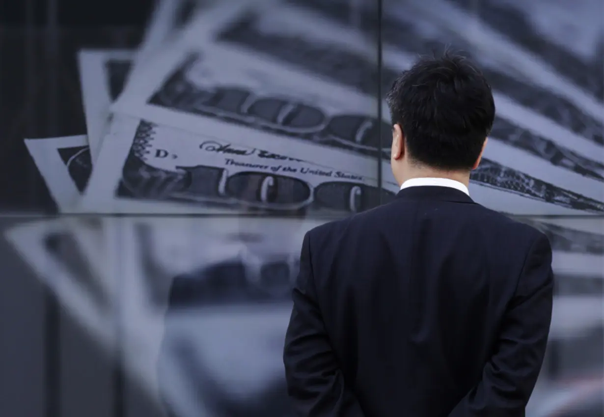 FILE PHOTO: A businessman looks at a screen displaying a photo of U.S. 100 dollar bank notes in Tokyo