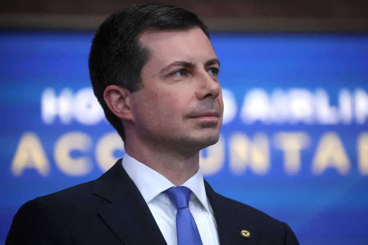 FILE PHOTO: U.S. Transportation Secretary Buttigieg listens as President Biden speaks at the White House in Washington, U.S.