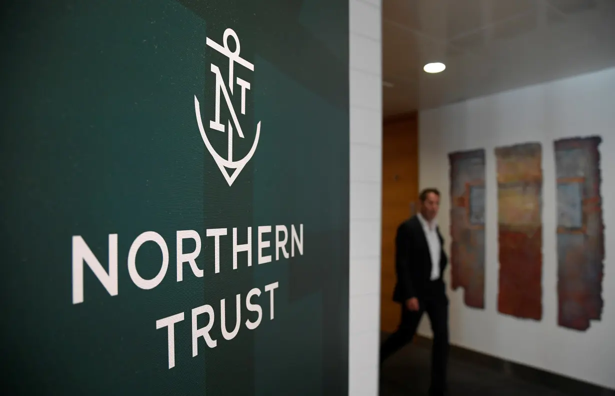 FILE PHOTO: An employee walks past a company logo at Northern Trust offices in London
