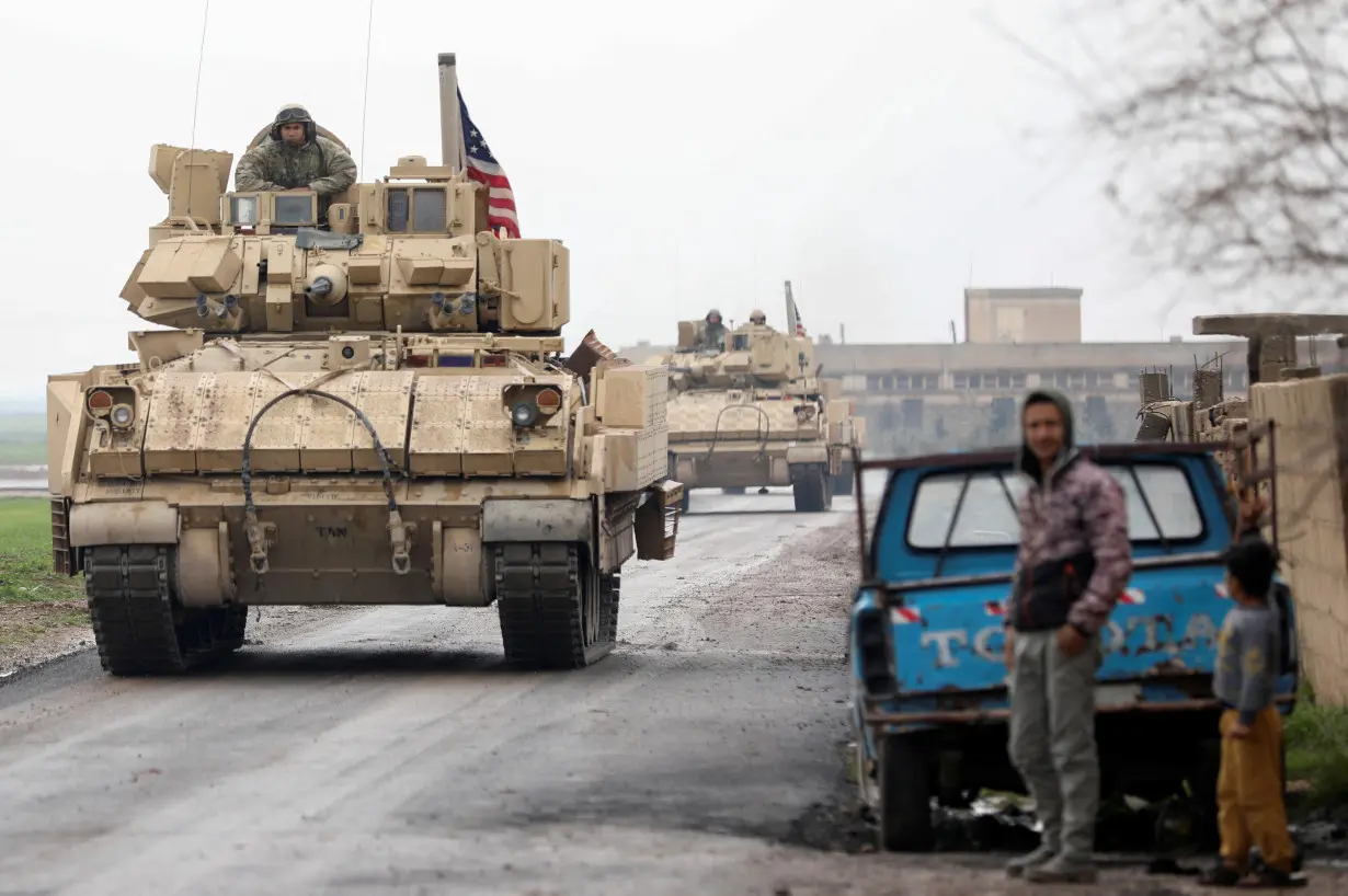 Residents stand on a street during a joint U.S.- Kurdish-led Syrian Democratic Forces (SDF) patrol in the countryside of Qamishli