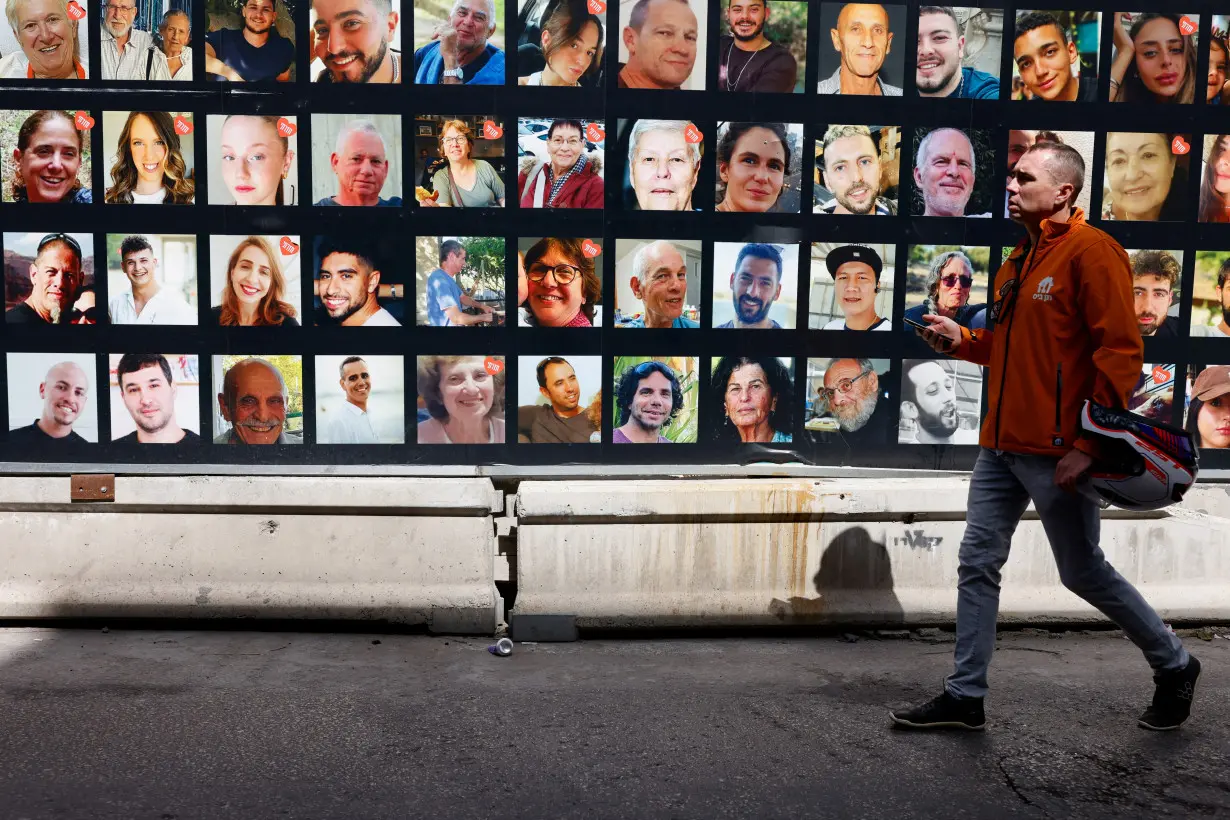 People walk past photos of hostages who were kidnapped in the deadly October 7 attack, in Tel Aviv