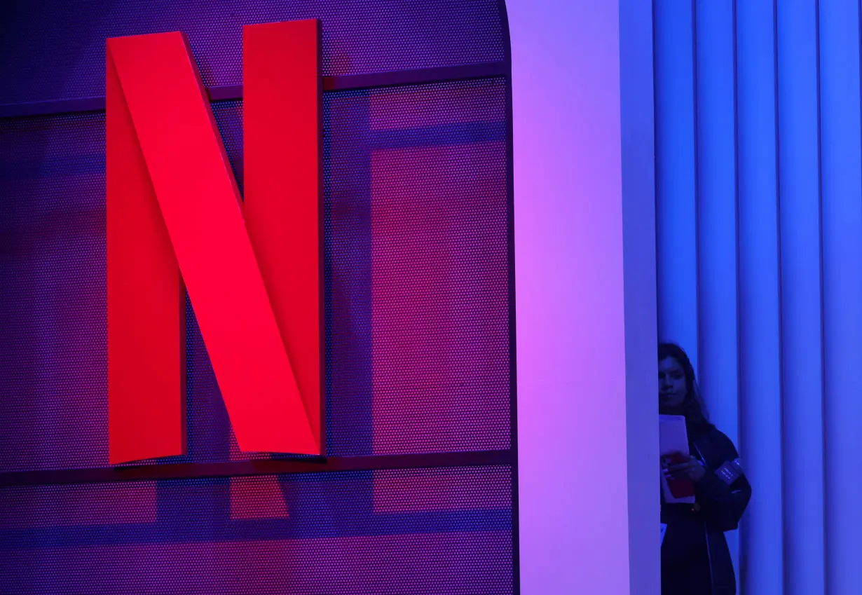 FILE PHOTO: A woman stands next to a logo of Netflix during an event in Mumbai