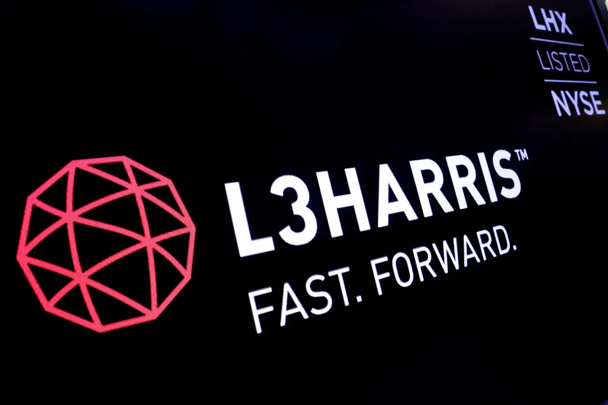 The logo and ticker for L3Harris are displayed on a screen on the floor of the NYSE in New York