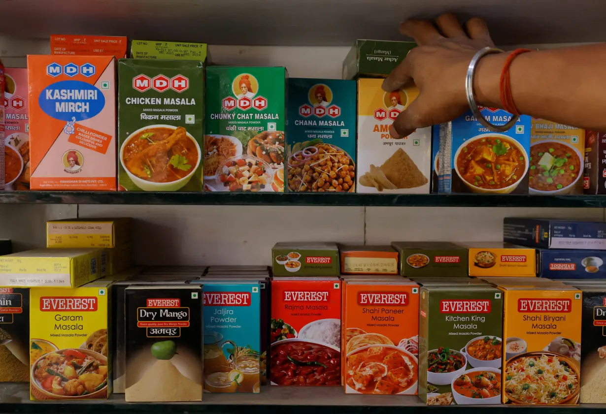 A man adjusts the spice boxes of MDH and Everest on the shelf of a shop at a market in New Delhi