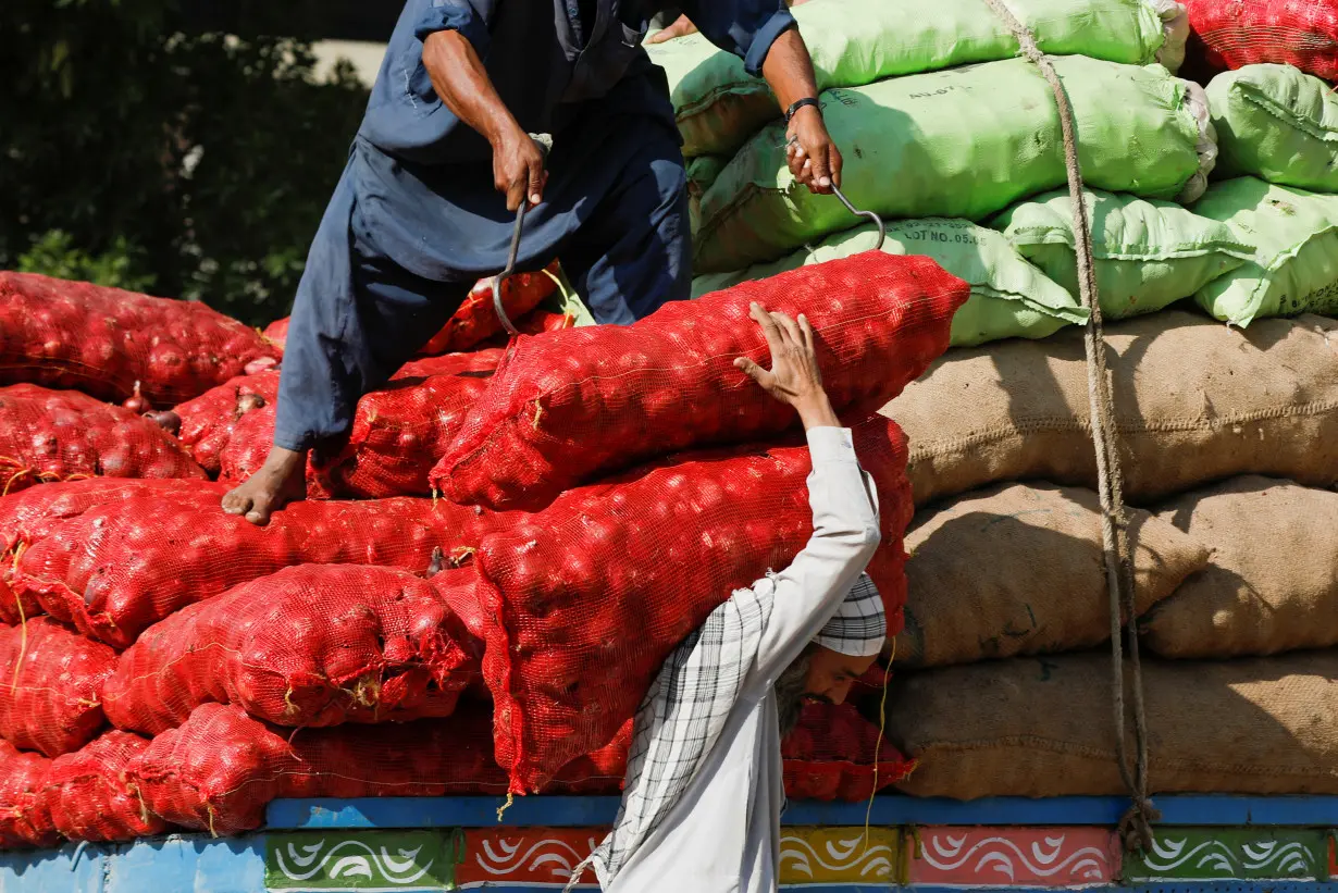 Labourers unload sacks of onion from a truck to supply at a market in Karachi