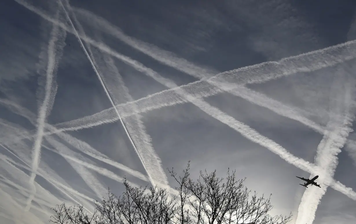 FILE PHOTO: A passenger plane flies through aircraft contrails in the skies near Heathrow Airport in west London