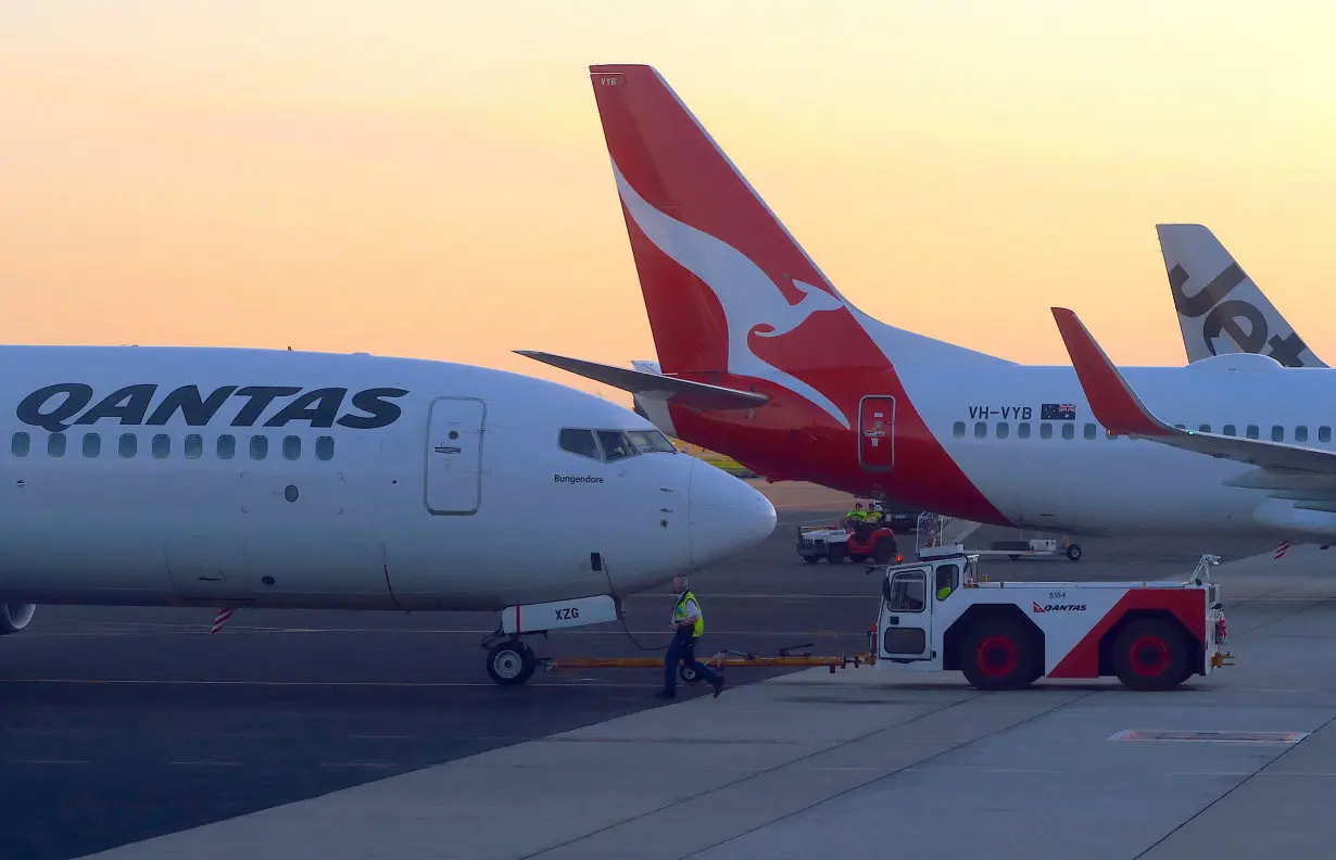 FILE PHOTO: Workers are seen near Qantas Airways, Australia's national carrier, Boeing 737-800 aircraft on the tarmac at Adelaide Airport