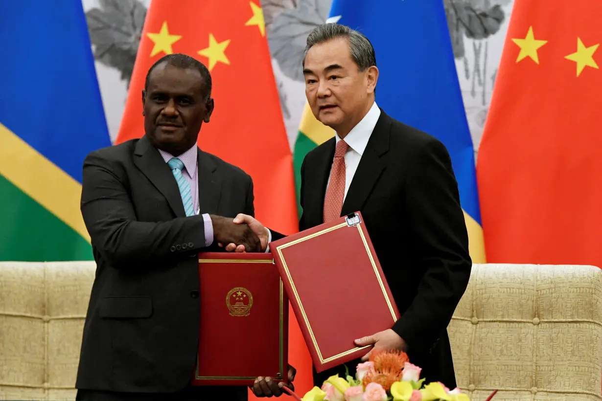 FILE PHOTO: Chinese State Councilor and Foreign Minister Wang Yi shakes hands with Solomon Islands Foreign Minister Jeremiah Manele during a ceremony in Beijing